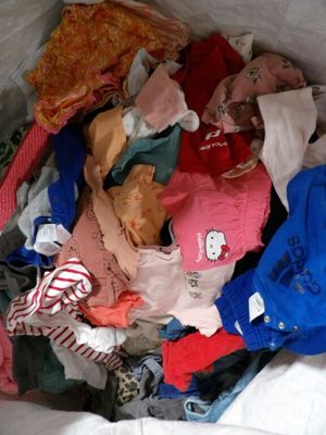 un sac blanc rempli de vêtements et des vêtements posés sur un lit