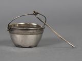 an antique silver cup with a spoon in it on a gray surface