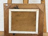 an old wooden easel with a picture frame on top of it next to a white wall