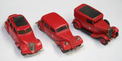trois petites voitures rouges posées les unes à côté des autres sur une surface blanche