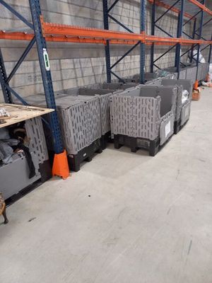 de nombreuses caisses et bacs dans un entrepôt, avec des cônes orange