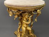une table en or avec un plateau en marbre sur lequel trône une statue