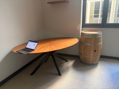 a laptop sitting on a wooden table next to a barrel of wine