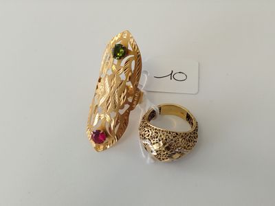 pair of gold rings with green and red stones on a white surface