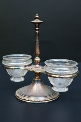 a silver candle holder with three glass bowls on top of it