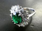 an image of a ring with a green stone surrounded by white diamonds