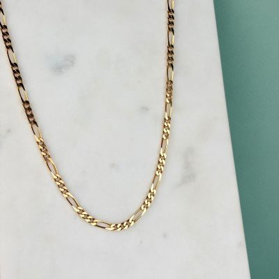 un collier à chaîne en or posé sur une dalle de marbre