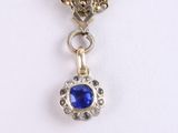 an image of a necklace with a blue stone hanging from a gold chain