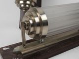 a metal object on a wooden stand with a glass tube