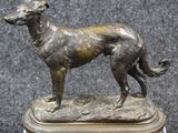 bronze statue of a dog on a wooden base on a black background