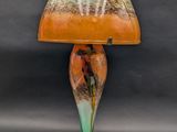 an orange and green lamp with a glass shade on it
