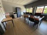 une pièce équipée d'une table, de chaises et d'un réfrigérateur