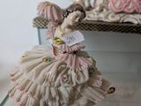 a figurine of a woman in a dress on a glass shelf
