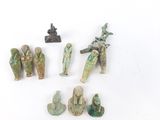 Plusieurs figurines anciennes sont exposées sur un socle blanc