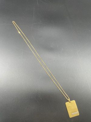 un collier plaqué or avec un pendentif de forme carrée monté sur une chaîne