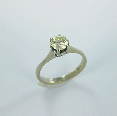 une photo d'une bague en diamant posée sur une surface blanche