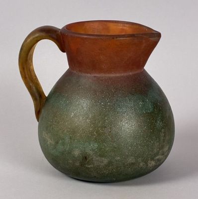 a brown and green vase sitting on a white surface