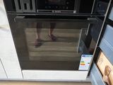 une personne debout devant un four dans une cuisine