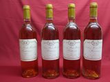 four bottles of wine are lined up on a pink background