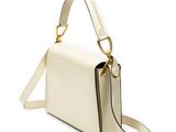 a white handbag with a gold handle on a white background