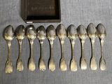 six cuillères en argent et une boîte contenant une brosse à dents, posées sur une table