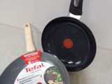 two frying pans sitting on the floor next to each other
