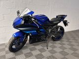 une moto bleue garée dans une pièce au sol carrelé