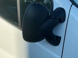 une camionnette blanche avec un rétroviseur latéral noir, garée sur le bord de la route
