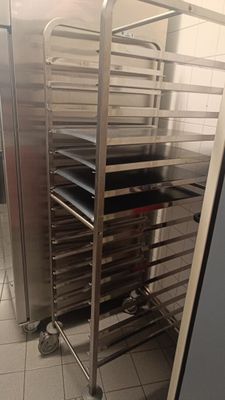 many trays of food sitting on a metal rack in the kitchen