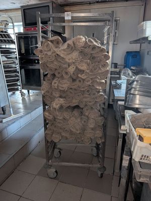 Plusieurs rouleaux de papier toilette sont empilés sur un chariot dans une cuisine