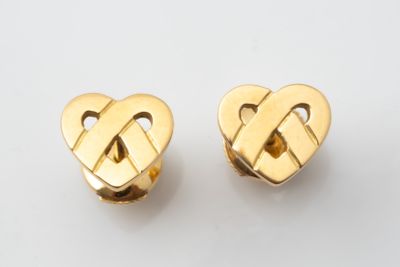a pair of gold heart shaped earrings on a white surface