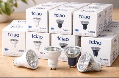 several different types of light bulbs sitting on a table next to a plant