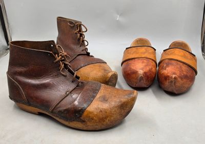 une paire de vieux sabots en bois posés sur une surface blanche