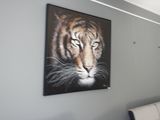 une photo d'un tigre accrochée au mur au-dessus d'un canapé