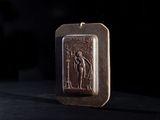 an image of a bronze pendant with a picture of a man holding a sword
