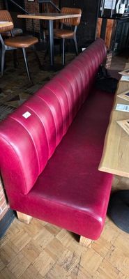 a red bench in the middle of a restaurant with wooden tables
