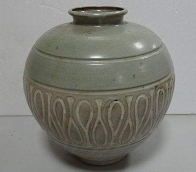 a green vase sitting on top of a white table
