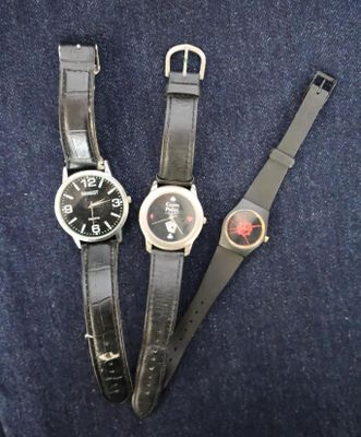 two black watches sitting next to each other on top of a blue cloth