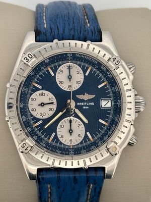 a close up of a watch with a blue leather strap