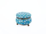 petite boîte recouverte d'un motif floral bleu et blanc, posée sur une surface blanche