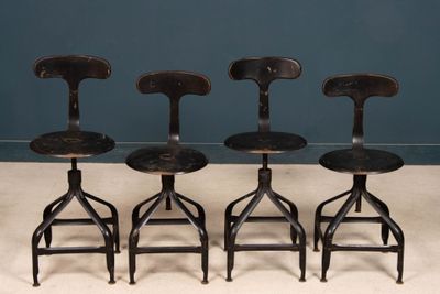four wooden stools sitting on top of a white floor next to a blue wall