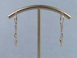 silver and gold plated earrings on a stand with a blue background