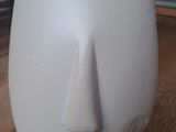 un vase blanc orné d'un visage, posé sur une table
