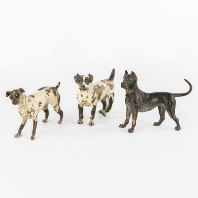 trois figurines de chiens alignées sur une surface blanche