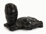 sculpture représentant une tortue posée sur un socle, sur une surface blanche