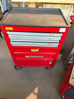 une boîte à outils rouge à roulettes et à tiroirs dans un garage
