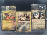 trois cartes Pokémon dans des pochettes en plastique, posées sur une table