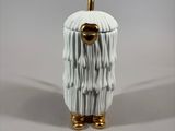a white ceramic object with a gold handle on a table