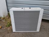 a white air conditioner sitting on the ground next to a garage door