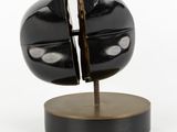 a sculpture of a black object on a wooden stand